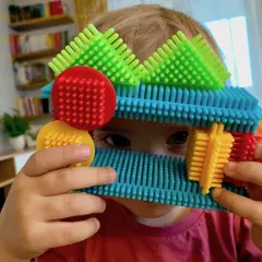 Dziecko bawi się kolorowymi klockami, które mogą być idealnym prezentem pod choinkę dla 2 latka.