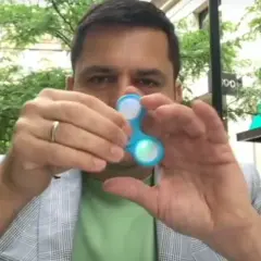 Mężczyzna trzyma niebieski spinner dla dzieci, który świeci.
