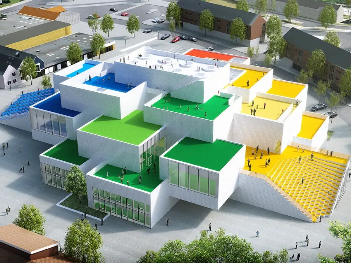 Architektoniczny cud w Danii, przypominający budowlę z klocków Lego, z kolorowymi dachami i tarasami, gdzie ludzie spacerują.